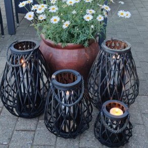 lanterner i sort flet med lys i st�r p� terrassen ved en blomsterkrukker med magurieter