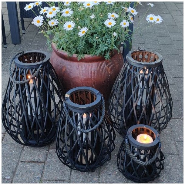 lanterner i sort flet med lys i st�r p� terrassen ved en blomsterkrukker med magurieter