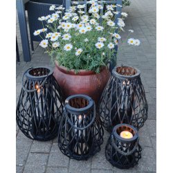 lanterner i sort flet med lys i st�r p� terrassen ved en blomsterkrukker med magurieter