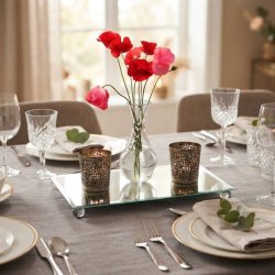 Elegant spejlfad brugt som midtpunkt p� et d�kket spisebord, prydet med en slank vase og lysestager.