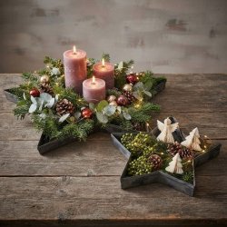 To stjerneformede zinkfade vist hver for sig, smukt dekoreret med gran, levende lys, julekugler og papirpynt.