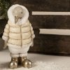 Et n�rbillede, der fokuserer p� den store variant (H20,5 cm) af pingvin-figuren. Billedet viser dens beige dunjakke med guldlynl�s, hvid pelshals og dens skinnende guldst�vler mod en rustik tr�kasse.