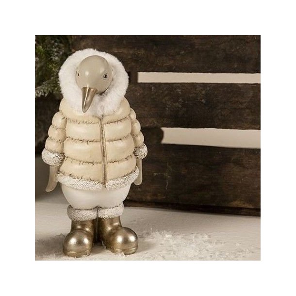 Et n�rbillede, der fokuserer p� den store variant (H20,5 cm) af pingvin-figuren. Billedet viser dens beige dunjakke med guldlynl�s, hvid pelshals og dens skinnende guldst�vler mod en rustik tr�kasse.