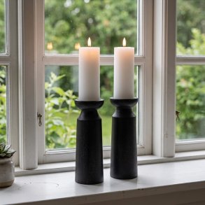To store, sorte tr�lysestager med t�ndte stearinlys st�r p� en hvid vindueskarm foran et vindue med udsigt til en gr�n have. En lille sukkulent plante i en krukke st�r til venstre.