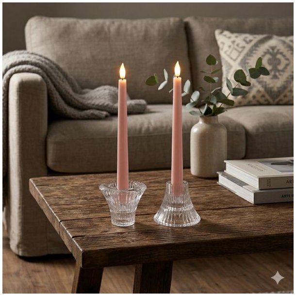 To vendbare lysestager i klart krystalglas med rosa kronelys opstillet p� et m�rkt tr�sofabord foran en sofa.