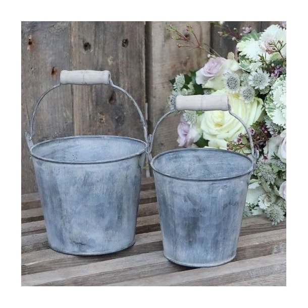 S�t med to rustikke zinkspande i en dekoration p� et tr�bord ved siden af en stor blomsterbuket.