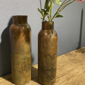 De to kobberfarvede jernvaser st�r sammen med en gren af rosa blomster i den ene vase, placeret p� en gammel tr�b�nk med en m�rkegr� v�g i baggrunden.