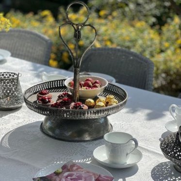 Kategoribillede til Fade og opsatser En s�lvfarvet opsats p� fod vist som inspiration til en kreativ bordopstilling med bloklys og boliginteri�r.