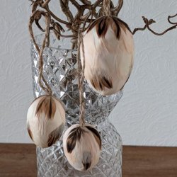 Tre lette creme-farvede p�ske�g med fjer og jutesnor h�ngende dekorativt p� for�rsgrene.