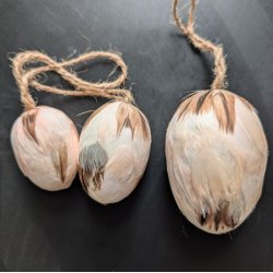 S�t med tre creme-farvede p�ske�g d�kket af fjer i st�rrelserne 5 cm, 6 cm og 8 cm