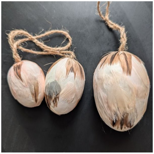 S�t med tre creme-farvede p�ske�g d�kket af fjer i st�rrelserne 5 cm, 6 cm og 8 cm